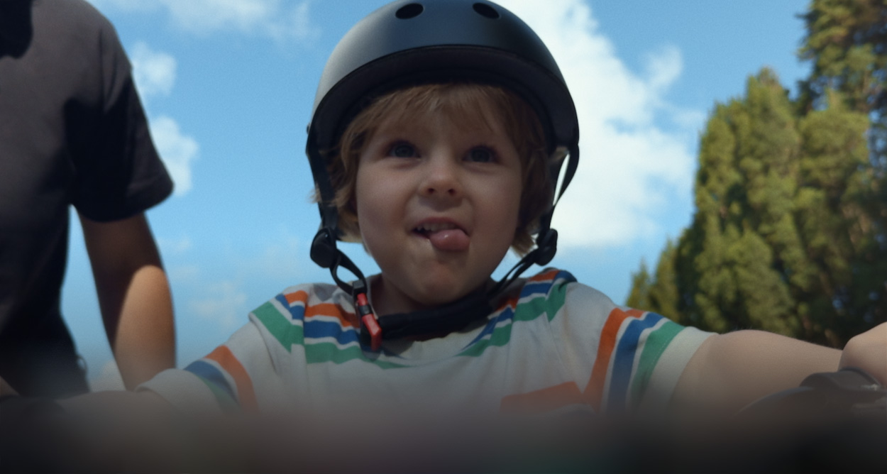 Child wearing a helmet on a bicycle as one parent guides him from behind